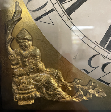 brass spandrel depicting a fire, leafless tree, and seated figure